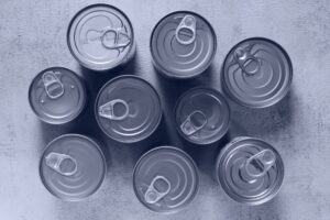 High-angle shot of canned food tins arranged on a rough surface, emphasizing texture and symmetry.