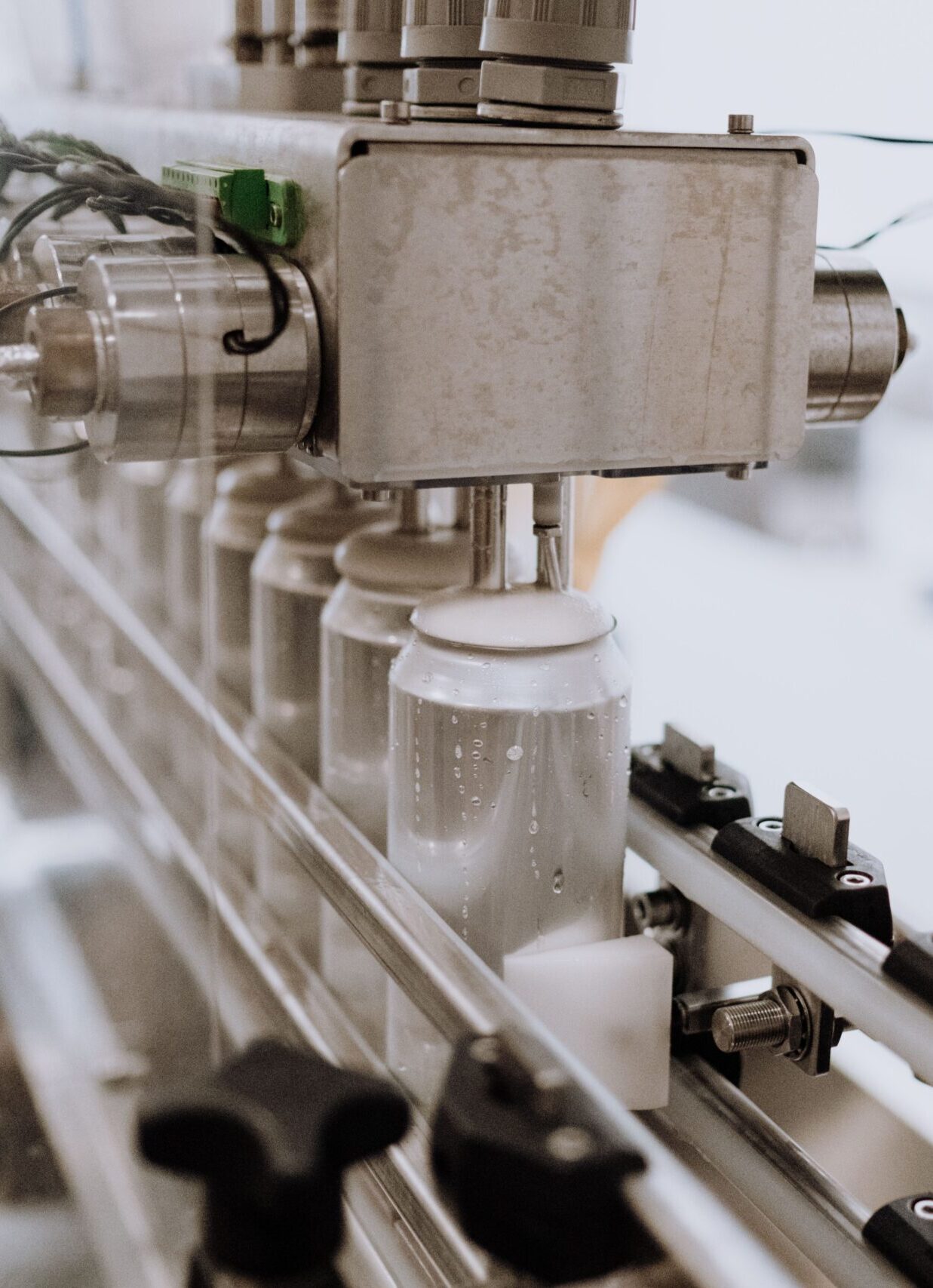 Close-up of an automated can filling machine in a beverage production line.